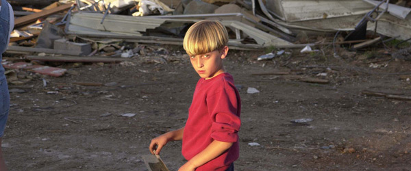 Un niño camina al lado de los restos de su hogar, que fue destruido por un tornado.